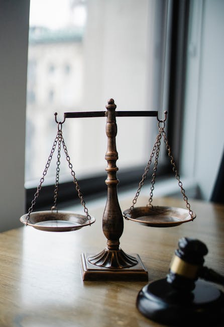 Bilancia della giustizia e martelletto del giudice su tavolo di legno, simbolo di equilibrio e applicazione della Legge di Ohm