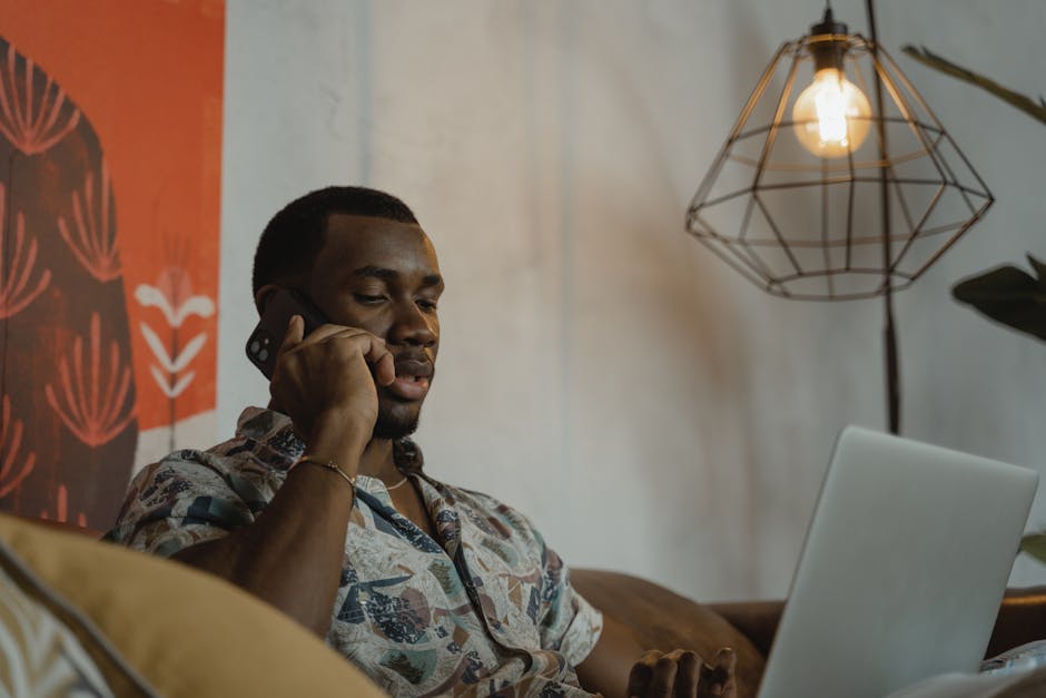 Uomo afroamericano che parla al telefono mentre lavora al computer, apprendimento e insegnamento innovativo