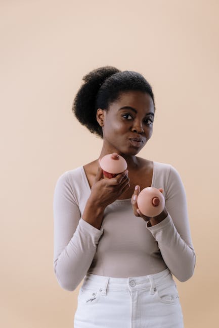 Donna sorridente tiene cupcake e sfera rosa a forma di seno per la Giornata dell'Alimentazione, sensibilizzazione e prevenzione.