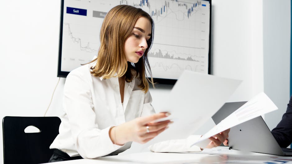 Analisi dati economici comparativi: giovane professionista esamina report finanziari in ufficio con grafici sullo sfondo, qualità della vita e sviluppo.