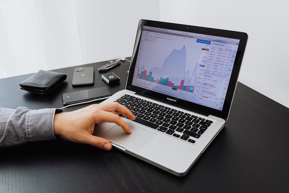 Monitoraggio business: uomo che analizza grafici su MacBook Pro per massimizzare l'efficienza aziendale e le strategie di crescita.