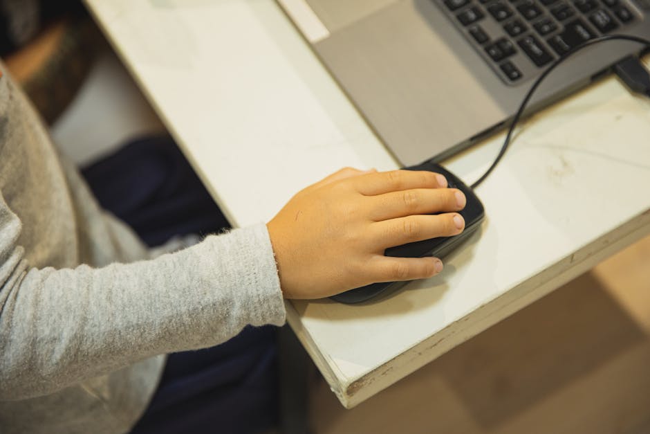 Mano di bambino che usa il mouse del computer, simbolo dell'educazione digitale e della protezione online dei minori