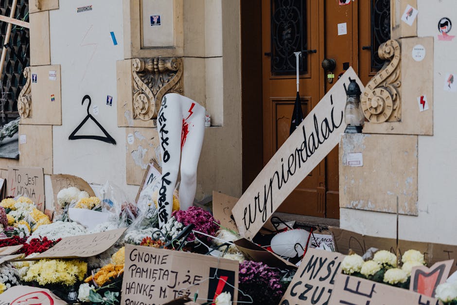 Protesta per i diritti delle donne e la Carta del Docente: cartelli, fiori e simboli di dissenso davanti a un edificio istituzionale.