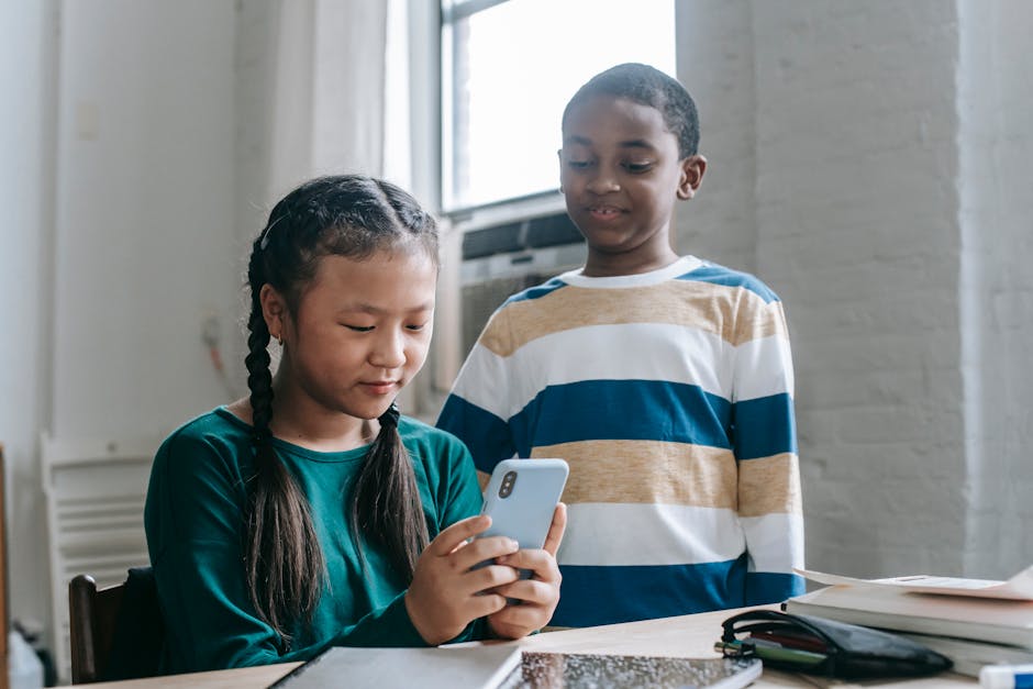 Ragazza asiatica usa smartphone in classe, compagno afroamericano osserva: impatto social media sui giovani, The Social Dilemma in classe.