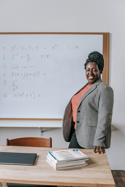 Insegnante sorridente spiega matematica alla lavagna durante corso di recupero scolastico per studenti con difficoltà