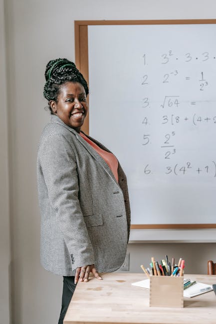 Docente sorridente davanti alla lavagna con formule matematiche. Opportunità di assunzione per i docenti in Sardegna nel 2026.