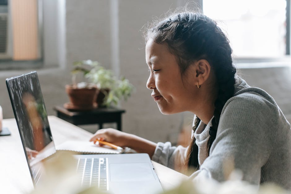 Ragazza asiatica studia online con laptop, disparità accesso internet nelle scuole primarie e istruzione digitale UNESCO