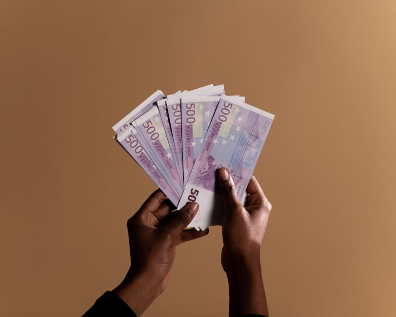 Stipendi laureati in Italia: mani che tengono banconote da 500 euro, divario salariale Nord Sud ed estero fino a 650 euro
