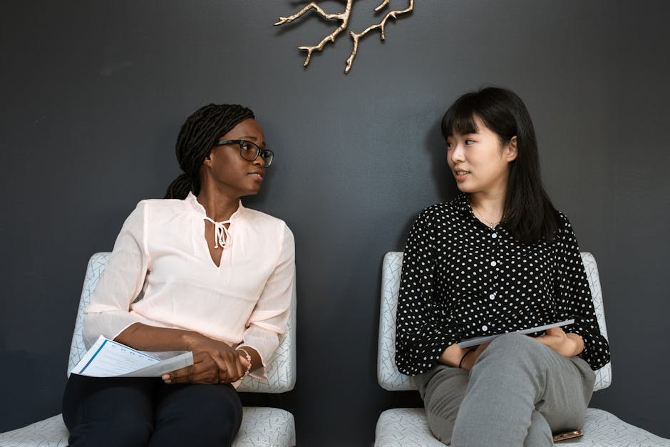 Due donne di etnie diverse sedute che discutono, simbolo di interazione culturale e scambio di idee per l'articolo Intersezioni.