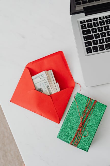 Carta docente e acquisti hardware: busta rossa con banconote, regalo verde e computer portatile, simbolo di investimento nell'istruzione.