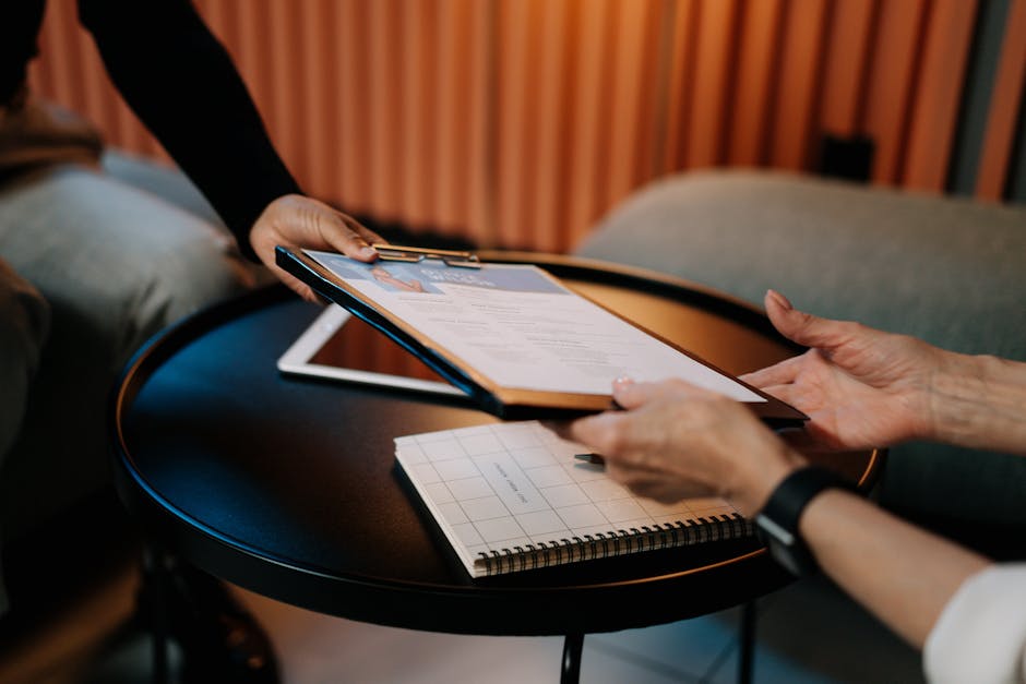 Domanda INPS Master Dipendenti Pubblici: mani che presentano curriculum vitae su tavolo con tablet e blocco note.