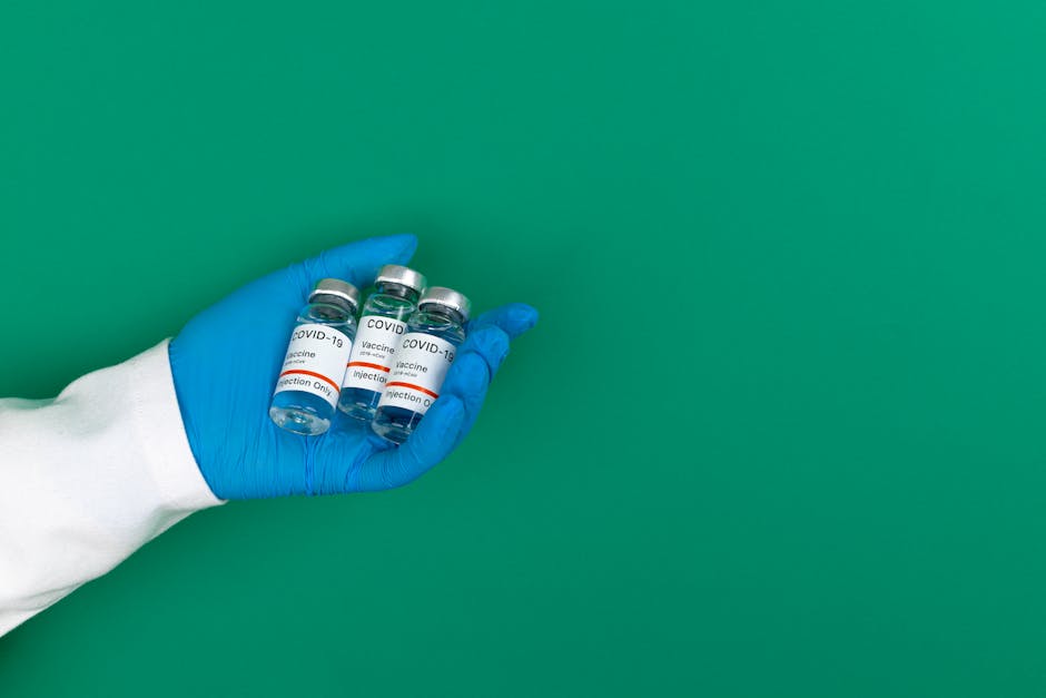 Fiale di vaccino COVID-19 tenute in mano con guanto blu, simbolo della ricerca genetica per malattie rare con AI