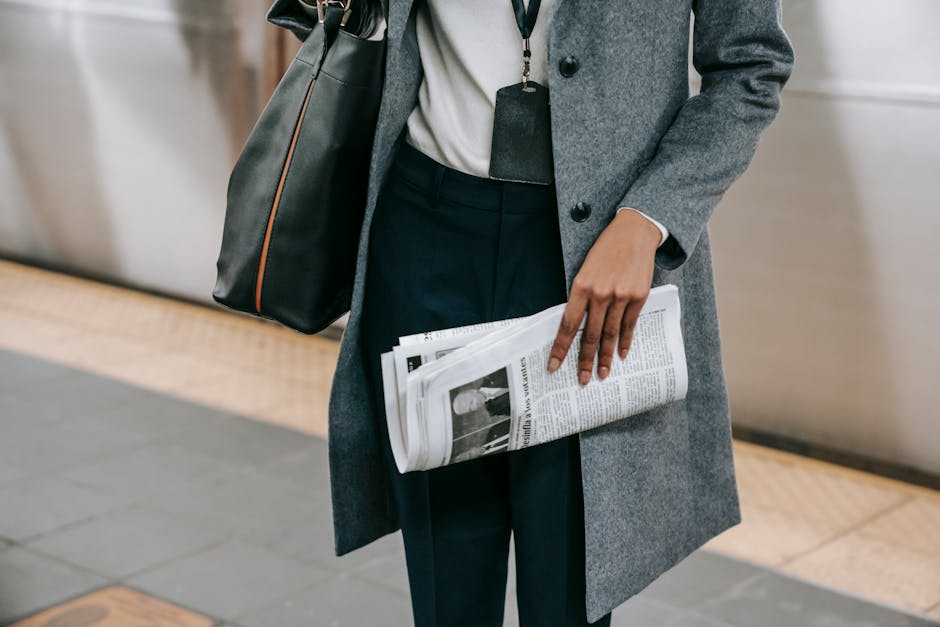 Donna in cappotto grigio con borsa e giornale, metafora di aggiornamenti ANAC e contratti pubblici online, procedure di acquisto.