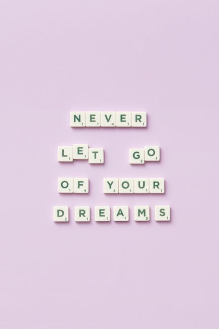 Non abbandonare i tuoi sogni: visualizzazione con tessere di Scrabble su sfondo lilla, ispirazione per raggiungere obiettivi e successo personale.