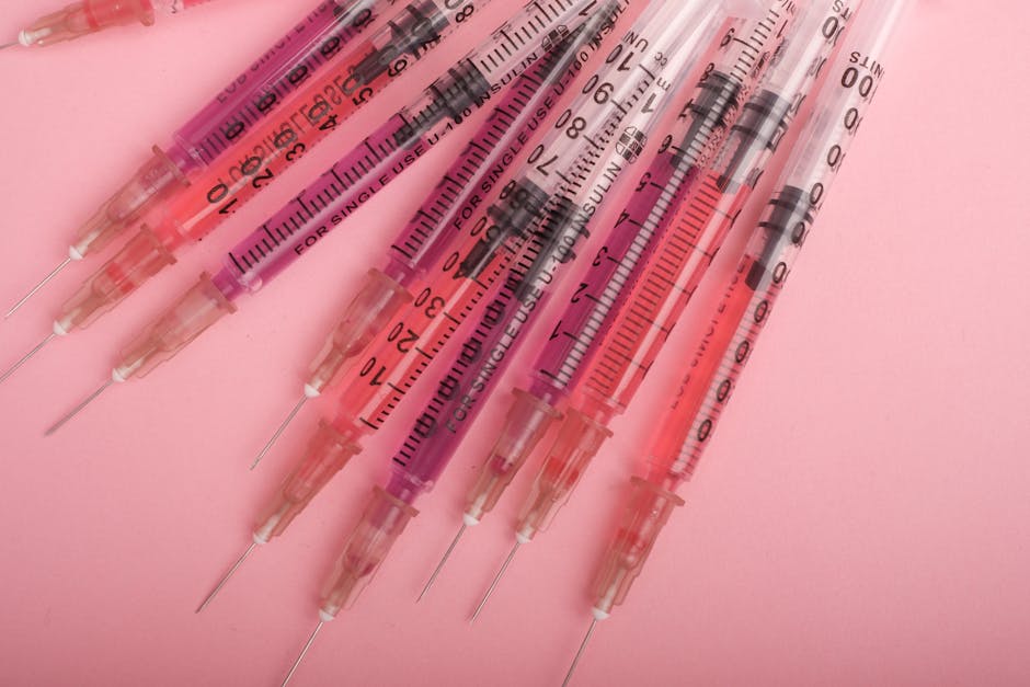 Siringhe monouso per insulina su sfondo rosa, dettaglio del processo diagnostico per una cura efficace e personalizzata.