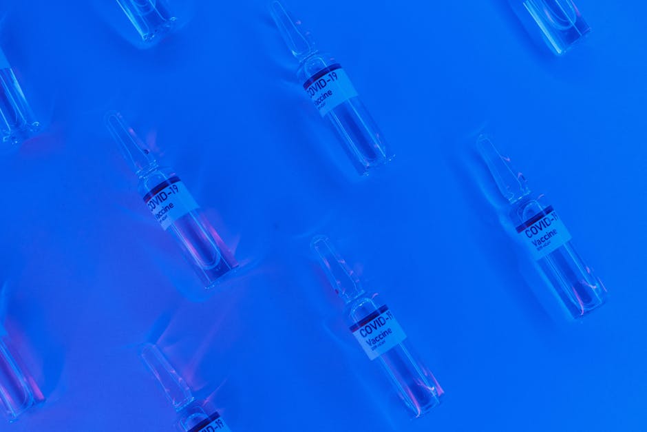 Fiale di vaccino COVID-19 su sfondo blu, simbolo di prevenzione e innovazione nella lotta alle malattie infettive e strategie di immunizzazione.