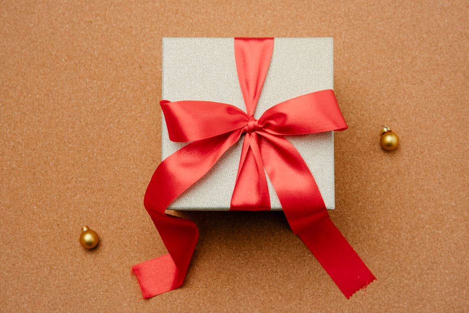 Regalo con nastro rosso e decorazioni dorate, simbolo di supporto economico per famiglie con permesso di soggiorno in attesa di occupazione.