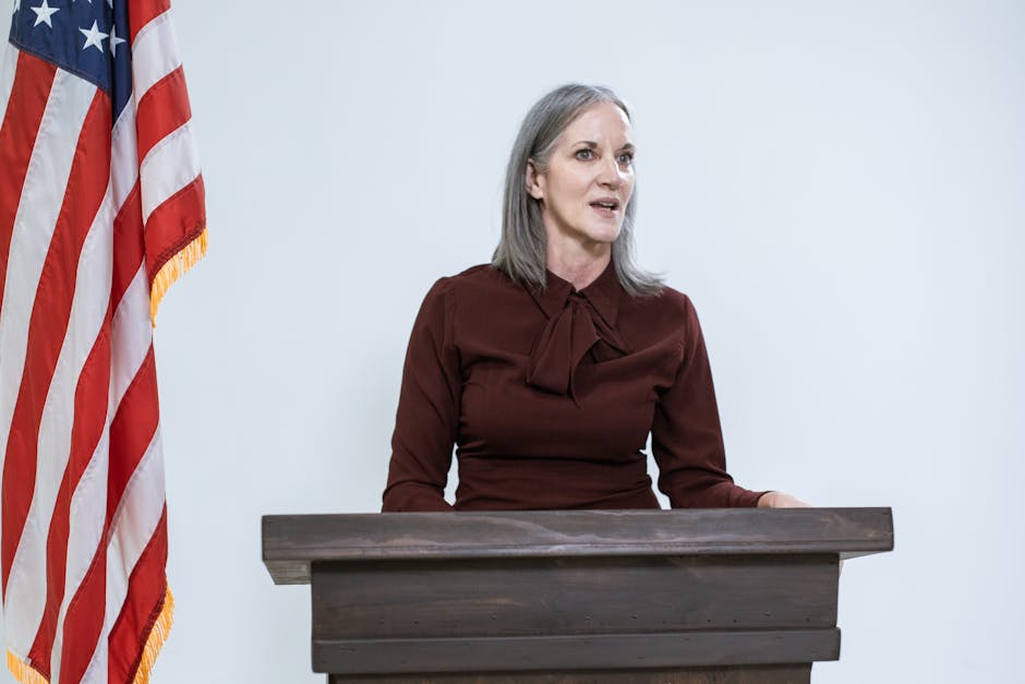 Nuovi direttori USR nominati: donna al podio con bandiera americana simbolo di leadership e decisioni in ambito scolastico