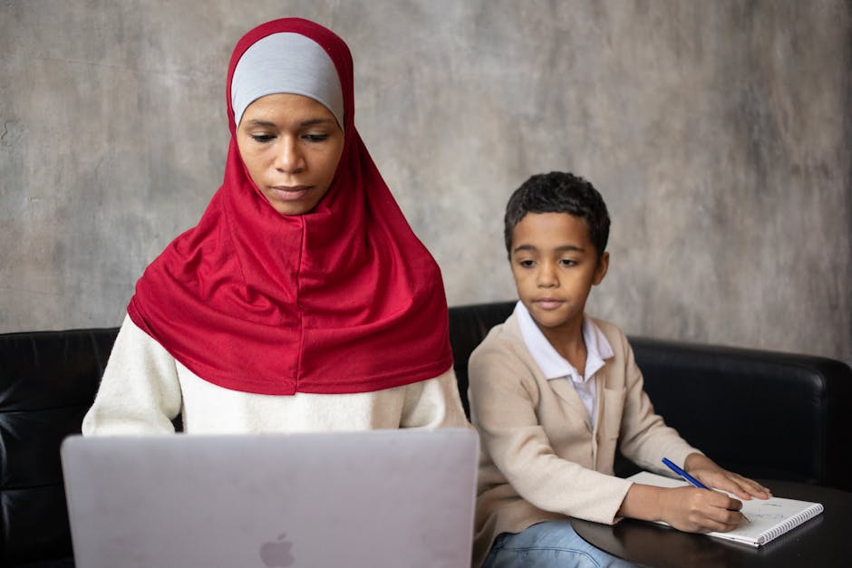 Apprendimento e tecnologia: madre e figlio studiano Madre con hijab e figlio studiano insieme usando laptop e quaderno, esempio di apprendimento moderno e tecnologia a scuola