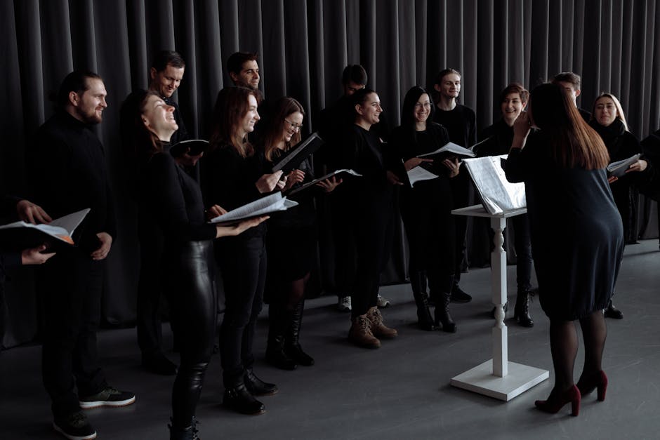 Coro che pratica il metodo di canto misto con entusiasmo e guida, espressioni di gioia e concentrazione durante la sessione vocale