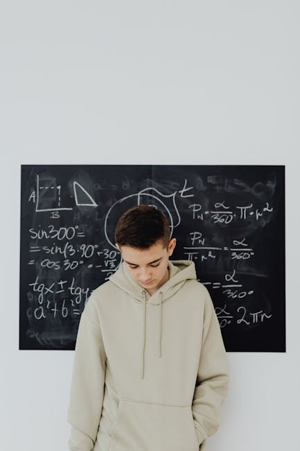 Studente pensieroso davanti a lavagna con formule matematiche, utile per articolo su MCD e risoluzione problemi matematici