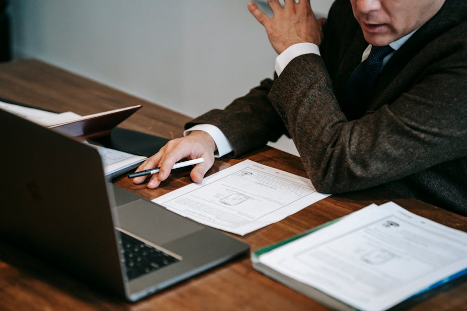 Docente al lavoro con documenti e laptop, riflessione sulla didattica e la demonizzazione della lezione frontale nel sistema scolastico.