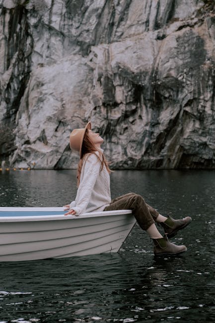 Donna su barca che galleggia, esempio del Principio di Archimede, con scogliera sullo sfondo e sguardo verso l'alto.