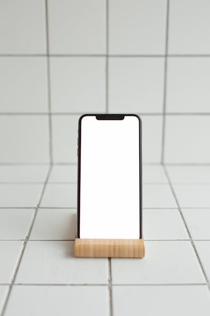 Smartphone con schermo bianco su supporto in legno, ideale per visualizzare un registro elettronico scolastico o app didattiche.