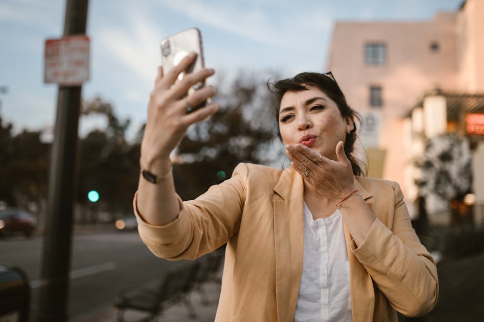 Donna sorridente che invia un bacio tramite videochiamata con smartphone, un esempio di mindfulness digitale e connessione online.