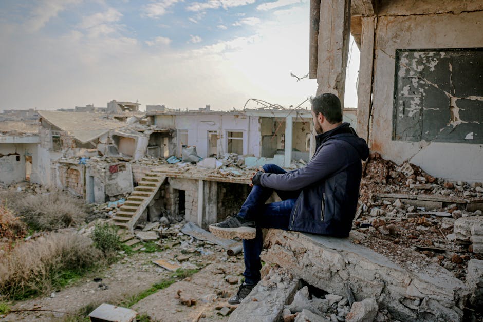 Giovane seduto tra le macerie di un edificio distrutto, simbolo della difficoltà abitativa e della precarietà giovanile in Italia.