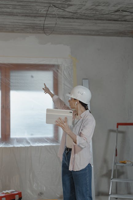 Tecniche di valutazione innovative: donna con tablet e casco analizza lavori di ristrutturazione per migliorare il progetto.