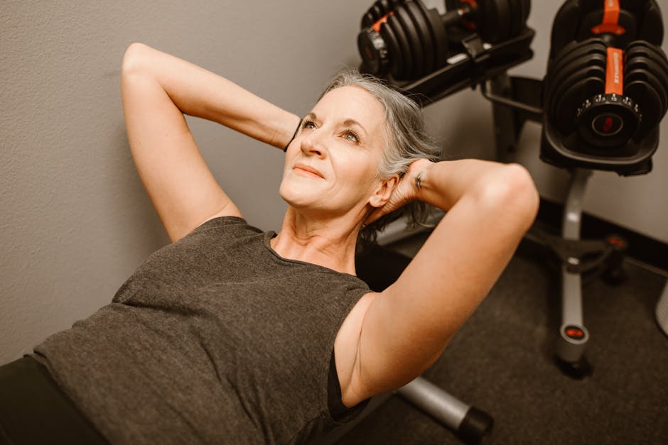 Donna over 65 fa esercizi addominali in palestra, mantenendosi attiva per una longevità sana e un ruolo attivo nella cura dei nipoti.
