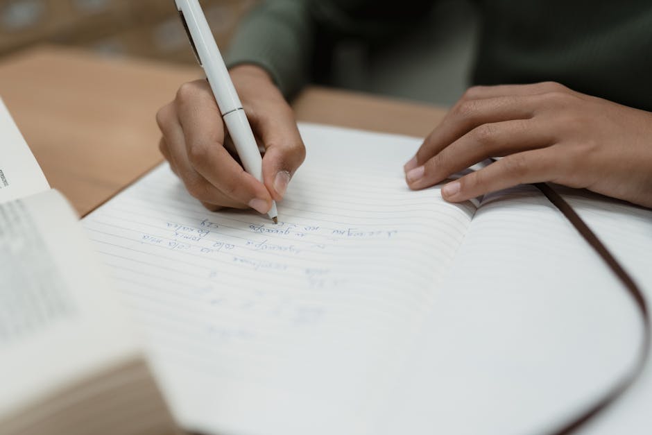 Studente scrive appunti su quaderno aperto, ispirazione per progetti di ricerca creativi e stimolanti per studenti universitari.