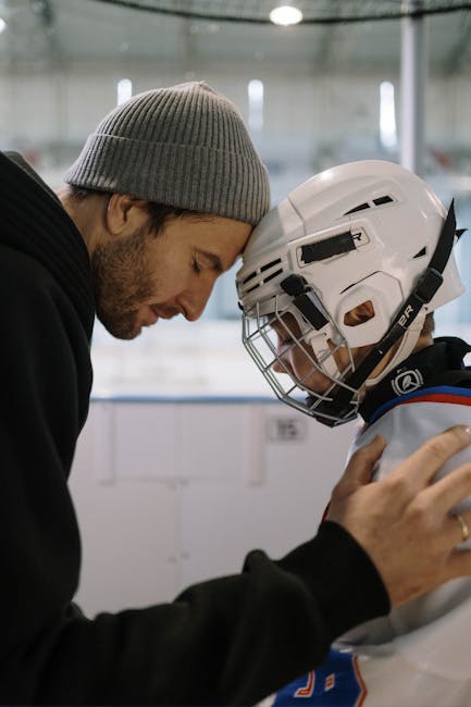 Padre conforta figlio con casco da hockey: un momento di tenerezza prima dell'inserimento scolastico, supporto emotivo e rassicurazione.