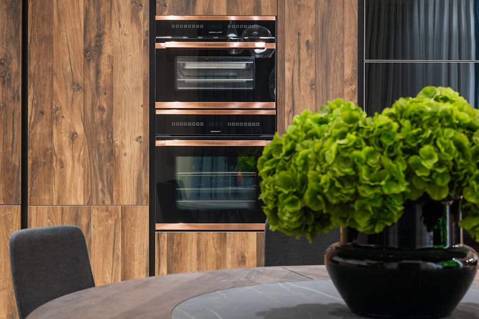 Cucina moderna con forno a incasso e dettagli in rame, design innovativo di Alex Neil per il settore immobiliare di lusso.
