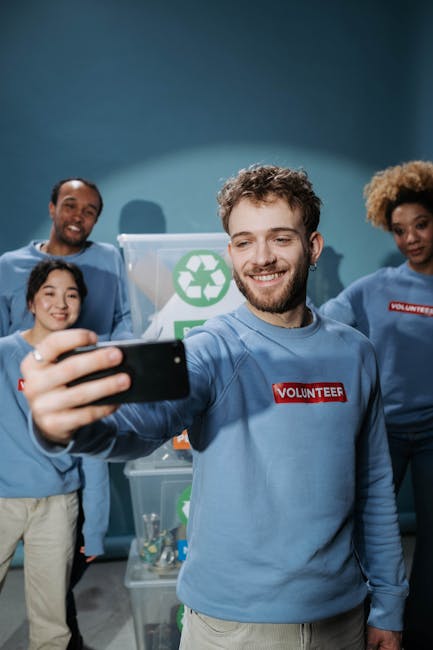 Volontari inclusivi sorridenti fanno un selfie davanti a contenitori di riciclaggio, promuovendo l'inclusione scolastica
