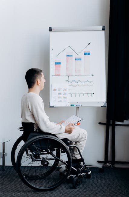 Uomo in sedia a rotelle esamina grafici: riflessioni sull'uso di terminologie obsolete e inclusione sociale delle persone con disabilità
