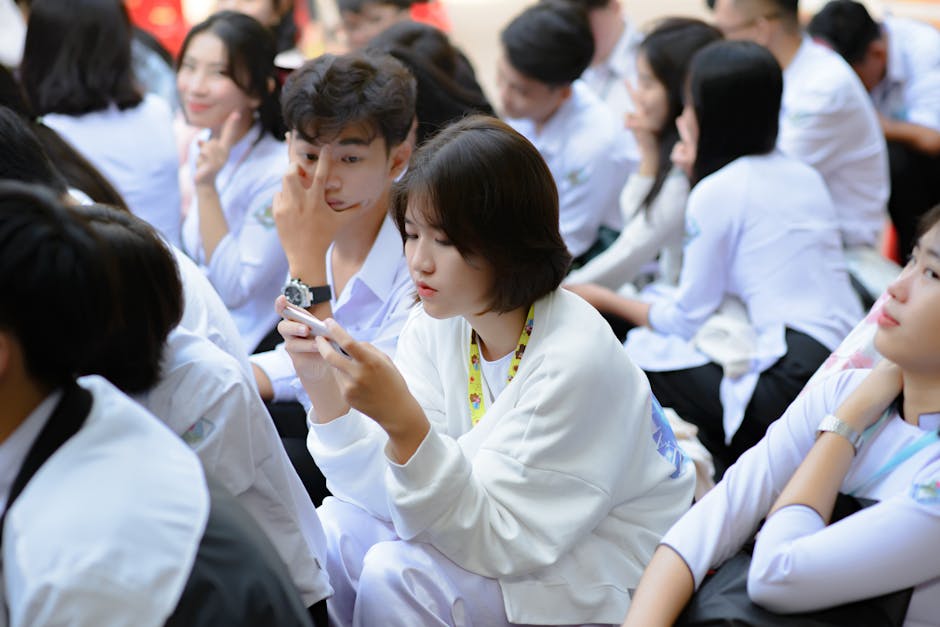 Studenti in aula con cellulari: riflessioni sulle nuove regole scolastiche e l'uso dei dispositivi mobili secondo Valditara. Focus su giovani e tecnologia.