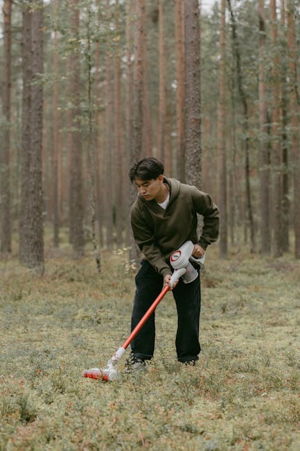 Uomo che aspira foglie nel bosco con aspirapolvere portatile, attività insolita per pianificazione del tempo e gestione dello stress.