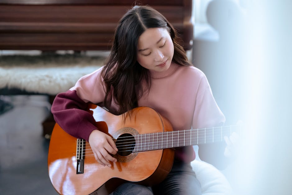 Ragazza asiatica che impara a suonare la chitarra classica, concentrata sulle corde, articolo su come imparare uno strumento musicale.