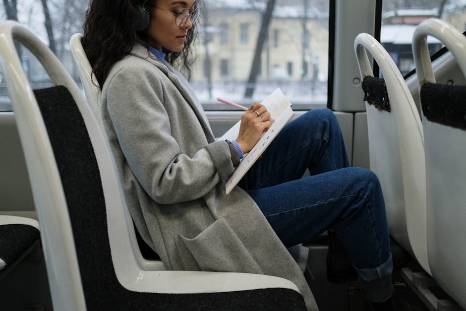 Donna con cuffie che scrive appunti musicali su un quaderno in treno, riflettendo sull'apprendimento attraverso la musica.