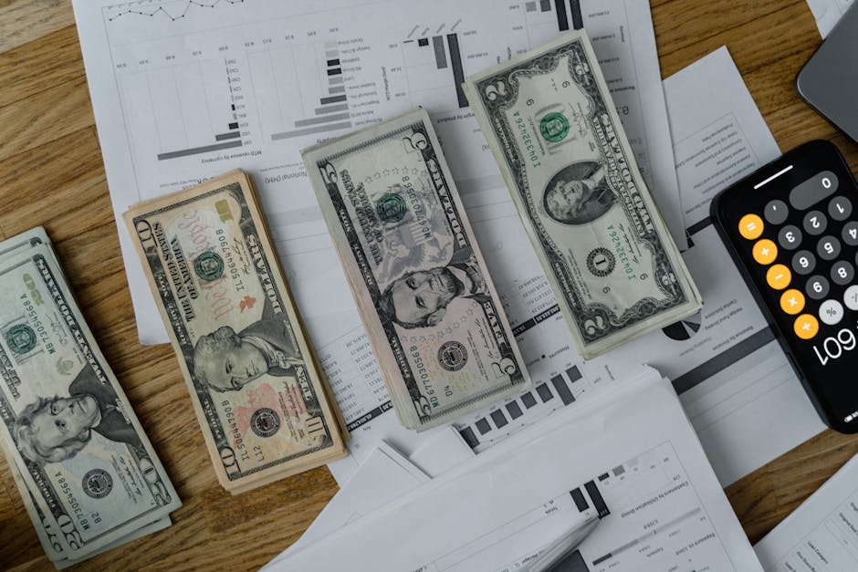 Aumenti salariali scuola: banconote dollari su grafici e calcolatrice, simbolo dei tempi di pagamento incerti per gli insegnanti.