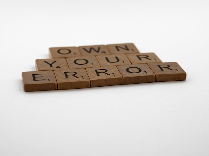 Tessere di Scrabble che compongono la frase 'Own Your Error', metafora per ammettere gli errori nella domanda GPS 2026 e correggerli.