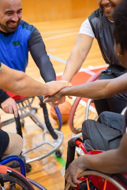 Giocatori di basket in carrozzina uniscono le mani: esempio di inclusione e supporto per studenti con disabilità.