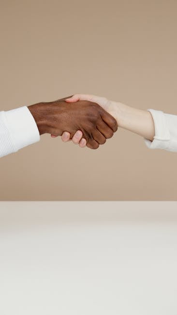 Stretta di mano interrazziale simbolo di rispetto e accettazione, unione di persone diverse per un futuro inclusivo e solidale.