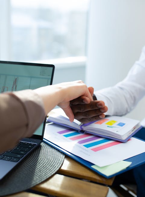 Finanziamento filiera tecnologico-professionale: mani che si toccano su grafici e laptop, simbolo di accordo e collaborazione