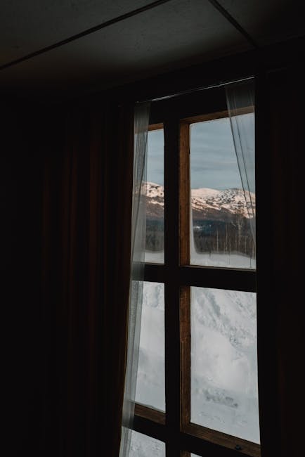 Finestra con vista sulle montagne innevate, simbolo di nuove prospettive e benessere mentale durante l'Erasmus.
