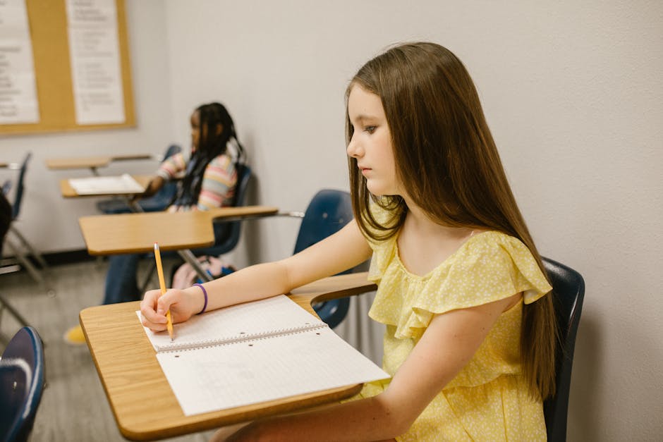 Ragazza scrive in classe: impegno scolastico contro bullismo e cyberbullismo per una scuola più sicura promossa da Valditara