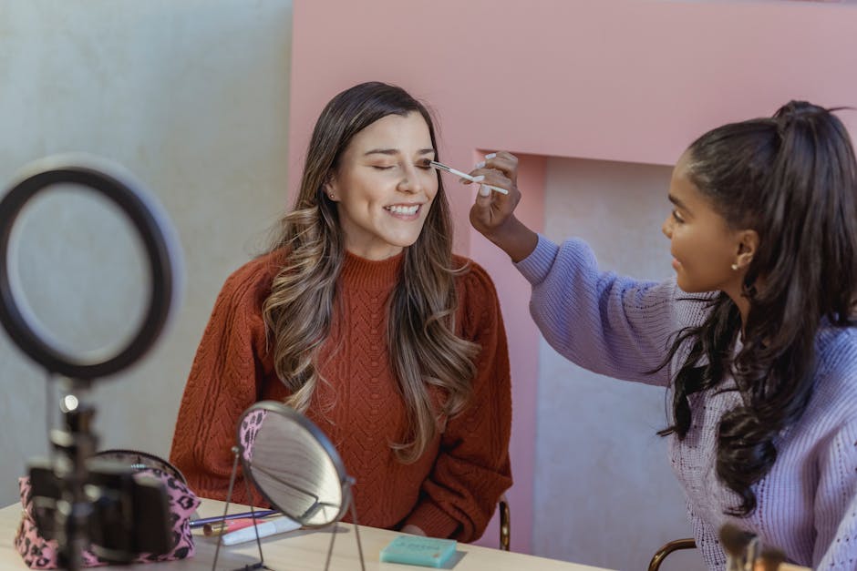 Tutorial trucco online: una ragazza applica ombretto a un'altra, ripresa con ring light, utile per concorso docenti PNRR3