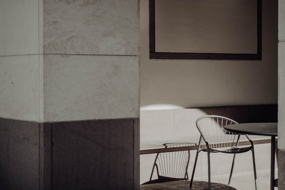 Angolo di un pilastro adiacente a sedie in un ambiente interno, illustrando concetti geometrici di adiacenza e angoli in architettura.